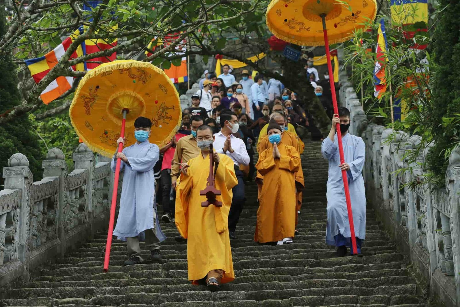 People in yellow robes descend a staircase, celebrating Buddha's Birthday with reverence and joy.