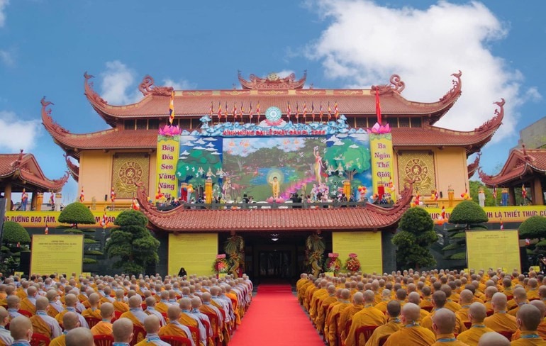 Buddhist monks attending a Vesak ceremony outside a decorated temple