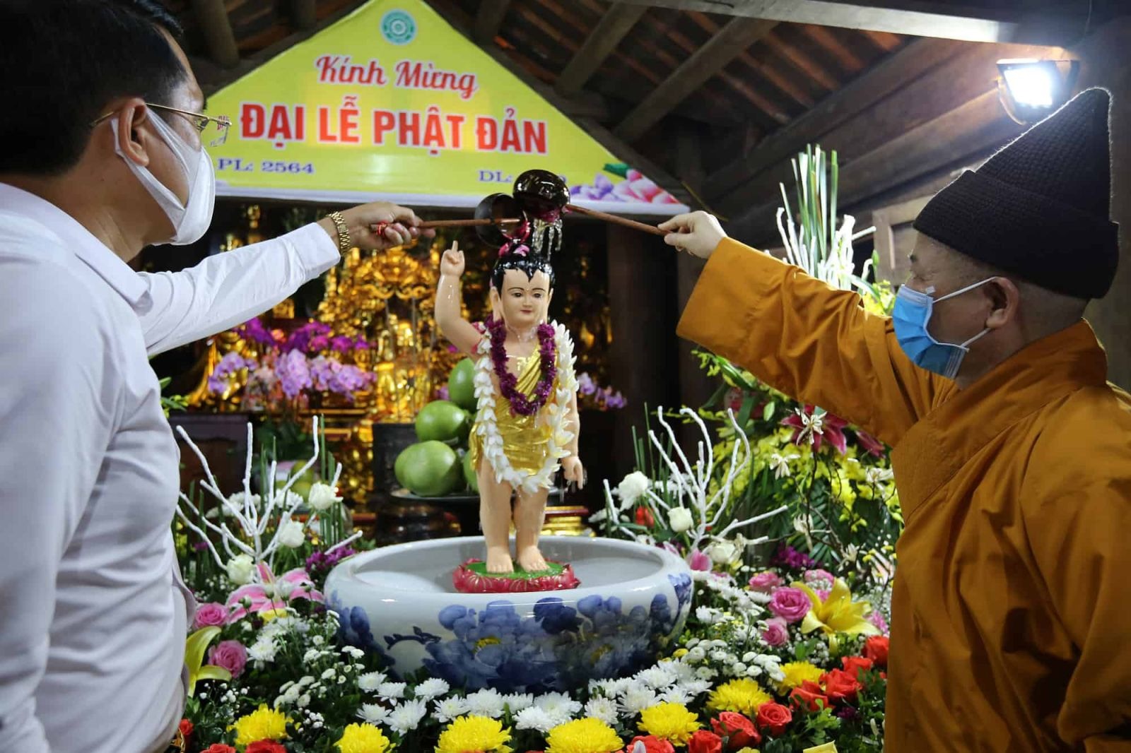 Monk performs a bathing ritual for a baby Buddha statue during Vesak