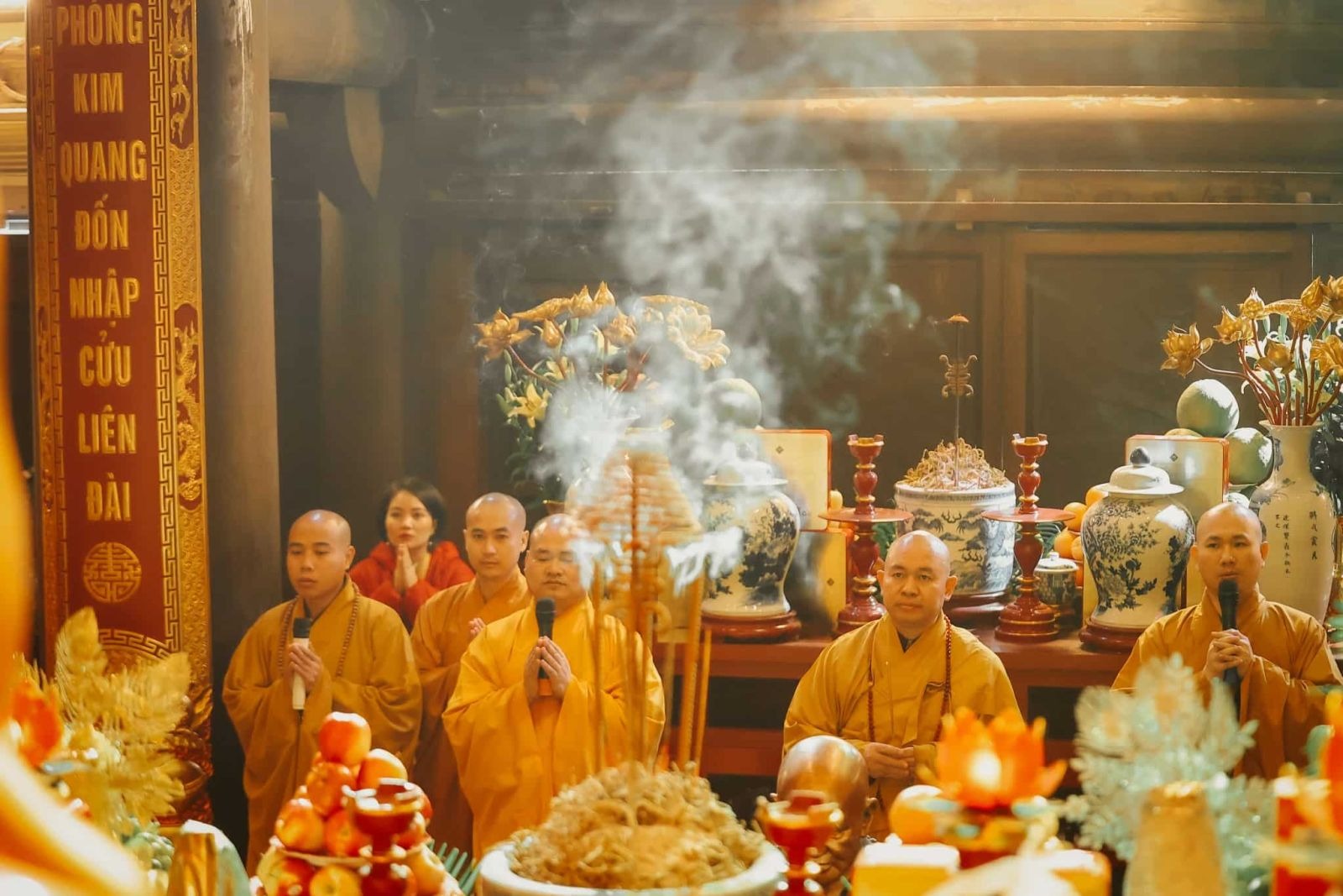 Buddhist monks chanting beside incense and offerings during a temple ceremony