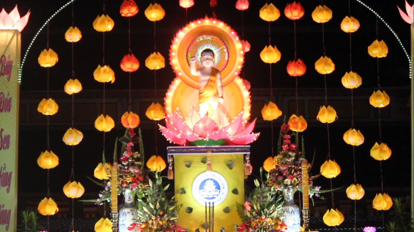 Illuminated baby Buddha statue surrounded by lotus lanterns at a Buddhist festival