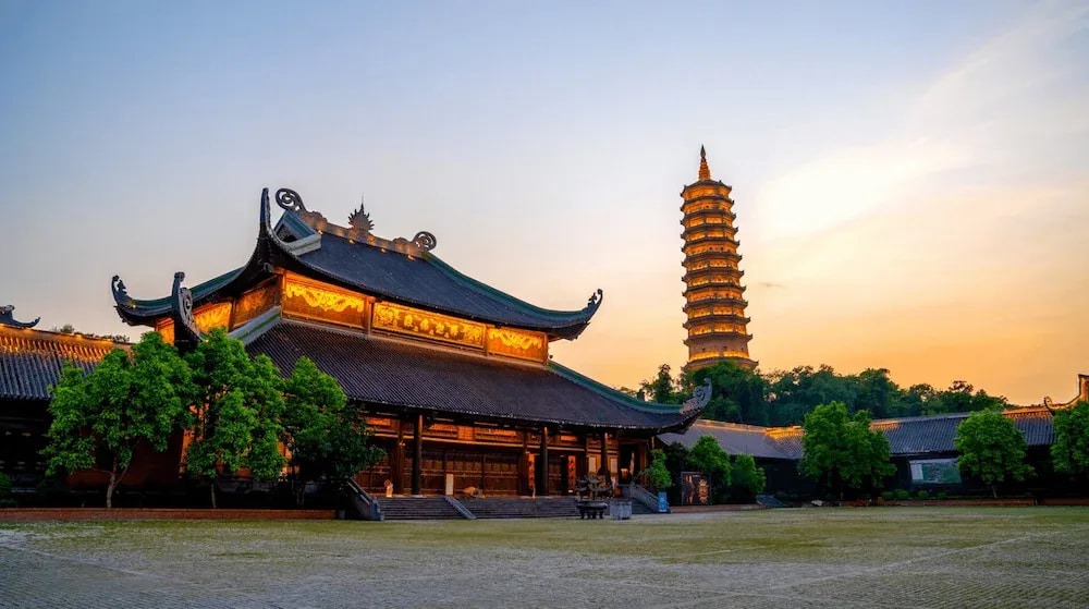 Bai Dinh Pagoda and illuminated tower at sunset in Ninh Binh